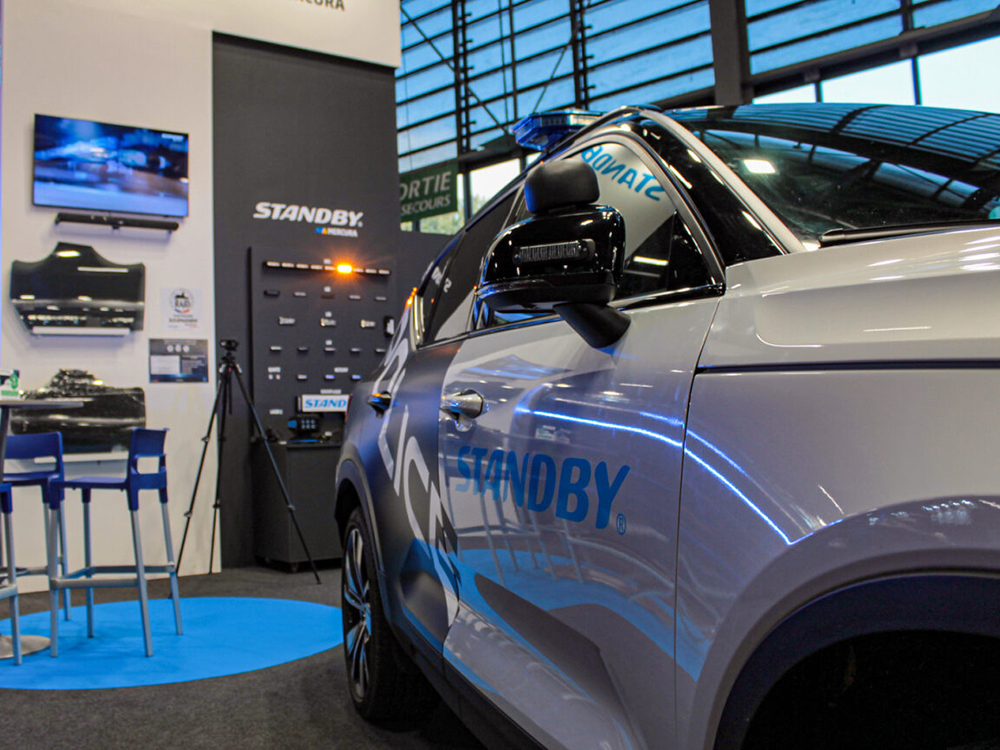 Close up shot of the Standby Mercura stand with an angle view of a car on the righthand side and products on wall in background.