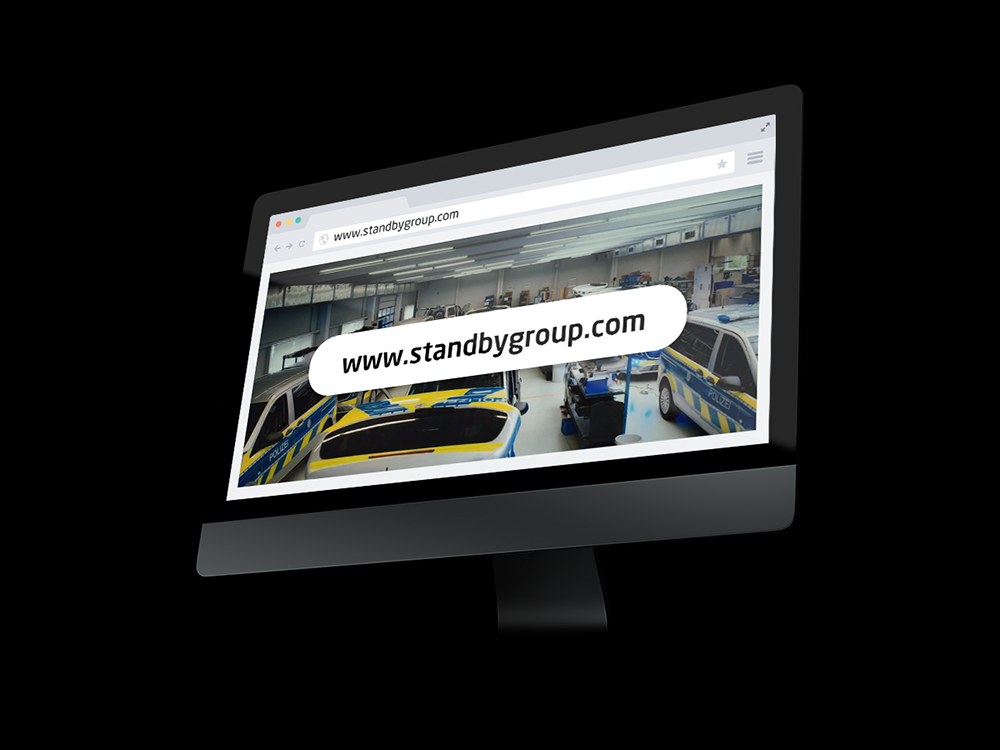PC screen mockup at an angle on a black background showing a webpage with a big banner reading 'www.test-1.standbygroup.com'.