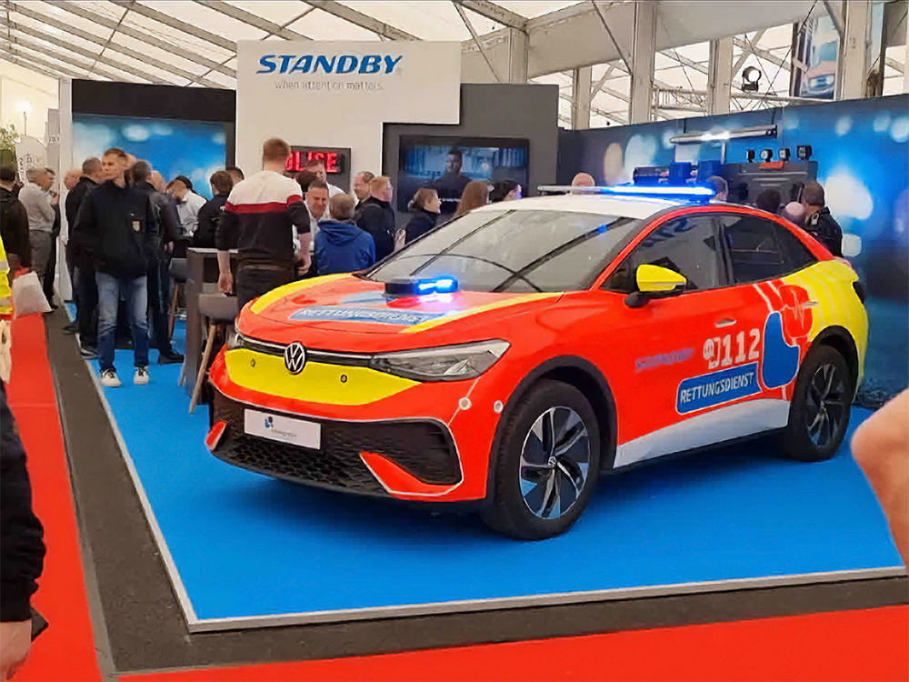 Busy Standby group stand with red response vehicle with blue lightbar in foreground and lots of visitors on the stand in the background.