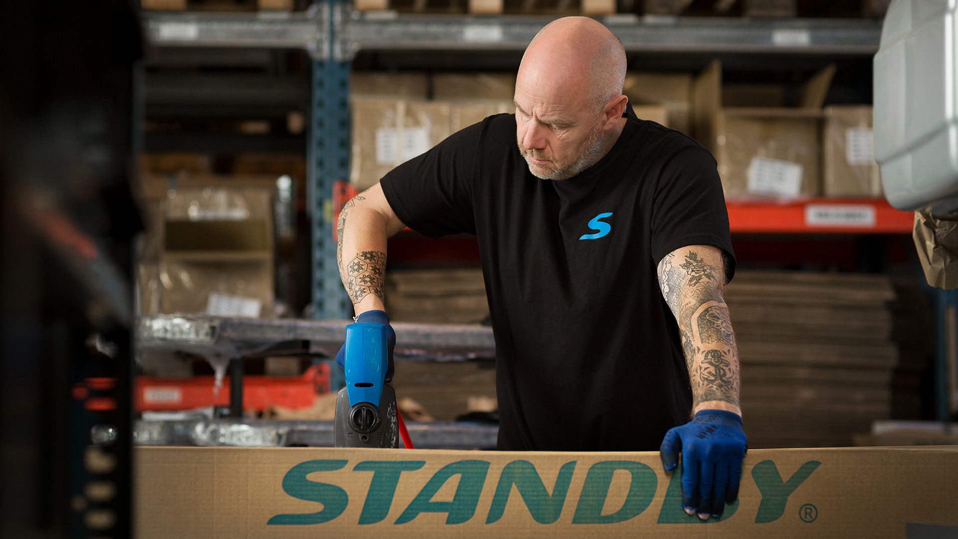 En medarbetare står och packar ihop en låda som det står Standby på.