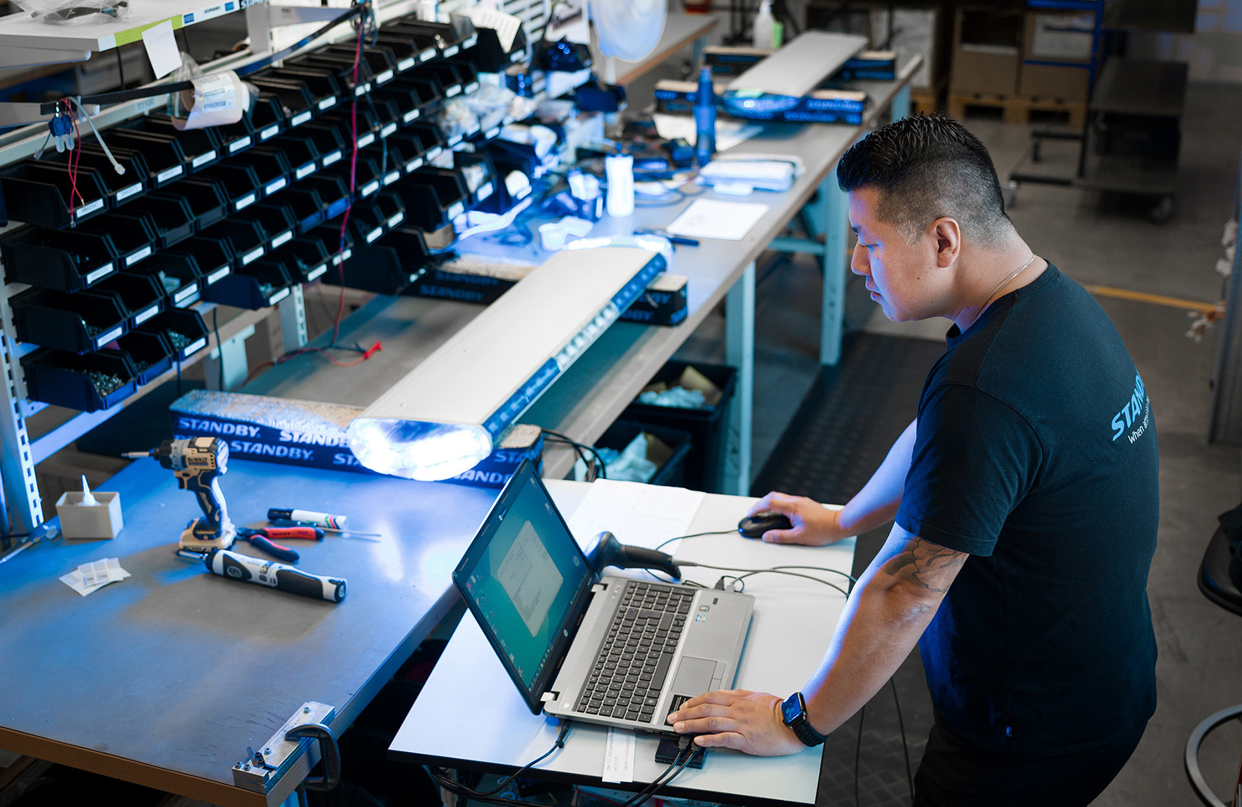 En medarbetare arbetar framför en bärbar dator med en ljusramp bredvid på en arbetsbänk.